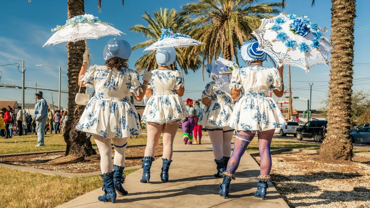 Festive women in costume participate in a vibrant New Orleans Mardi Gras parade.