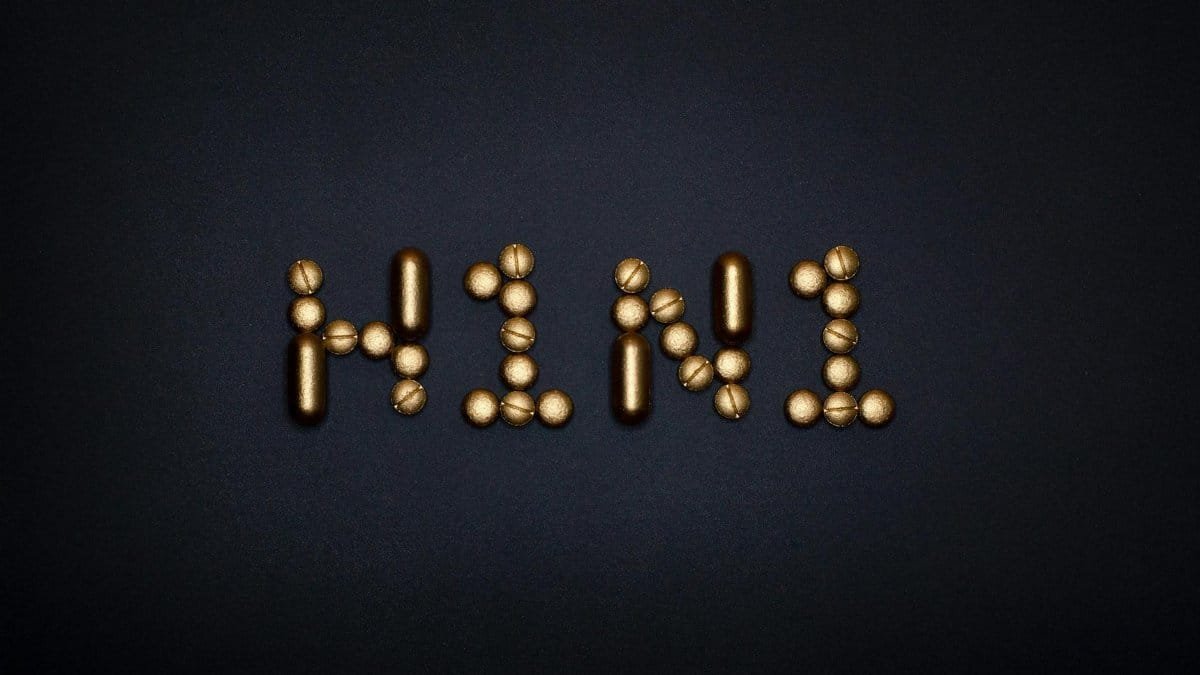 Elegant arrangement of gold pills spelling H1N1 against a black surface, symbolizing healthcare and medication.
