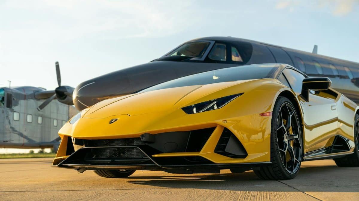 Yellow Lamborghini sports car parked next to a private jet on an airport runway in Illinois.
