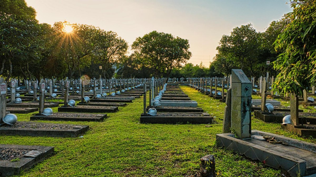 National main heroes cemetery with abundance of tombstones with military hardhats located in national cemetery with green trees in Kalibata