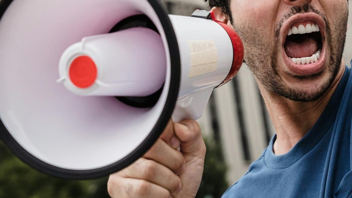 Close-up of a man passionately shouting through a megaphone during a protest.