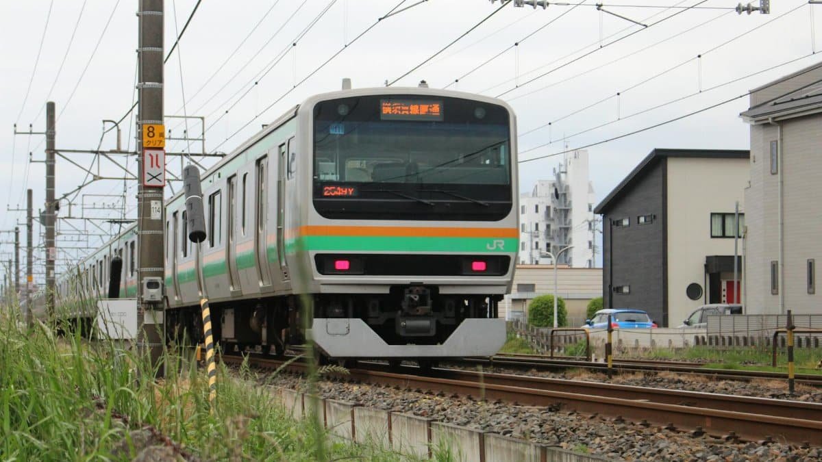 A commuter train traveling on tracks in Utsunomiya City, Japan, captured from the front view on a clear day.