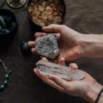 Close-up of hands holding healing crystals, surrounded by natural gemstones and a beaded bracelet.