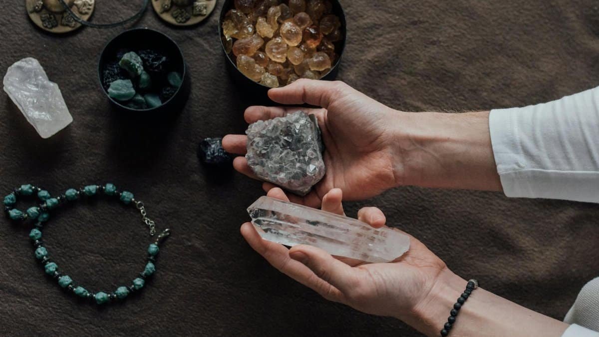 Close-up of hands holding healing crystals, surrounded by natural gemstones and a beaded bracelet.