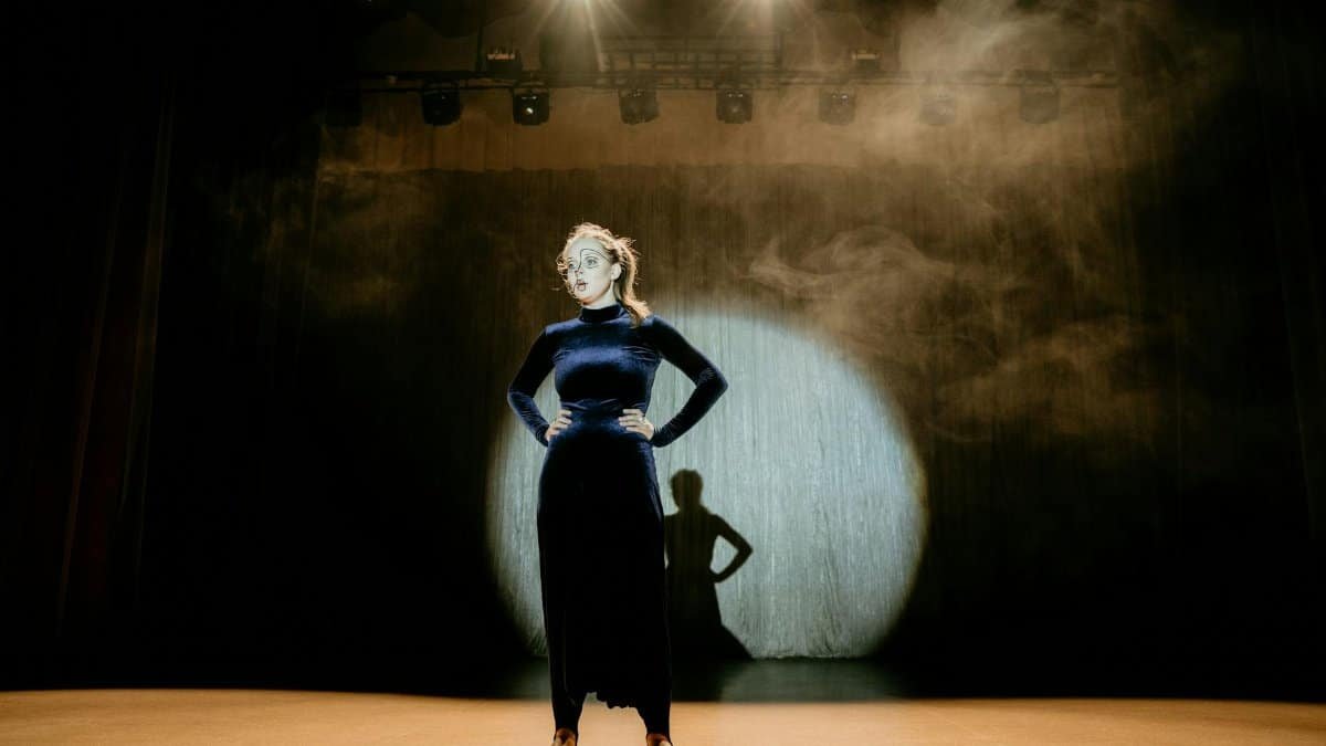 Captivating shot of a performer in a velvet dress on stage under dramatic lighting.
