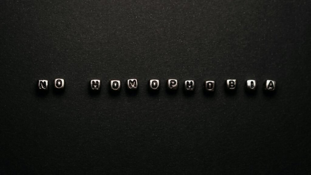 Silver letter beads spelling 'No Homophobia' on a black surface, symbolizing a message of equality.