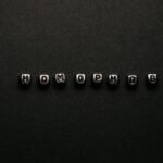 Silver letter beads spelling 'No Homophobia' on a black surface, symbolizing a message of equality.