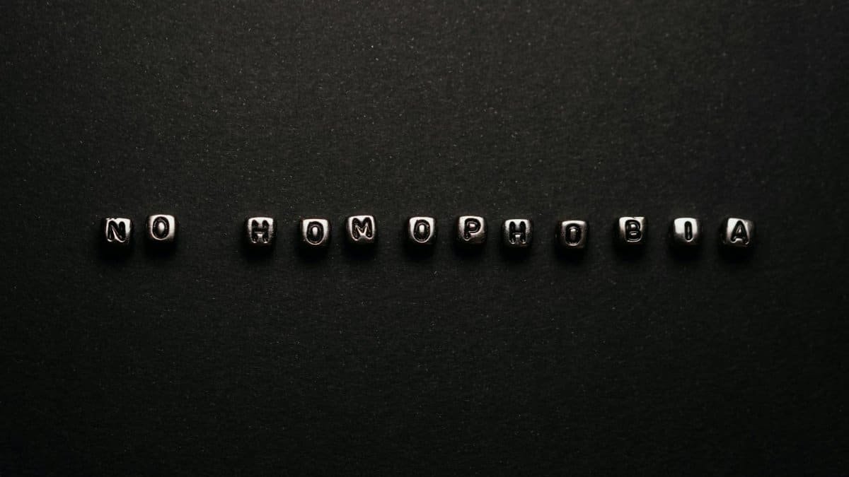 Silver letter beads spelling 'No Homophobia' on a black surface, symbolizing a message of equality.