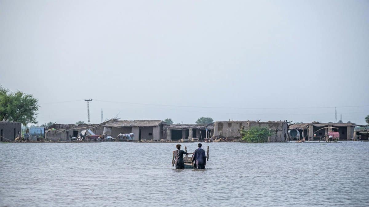 People wading through floodwaters in Gandakha City, highlighting the impact of the 2022 floods in Balochistan, Pakistan.