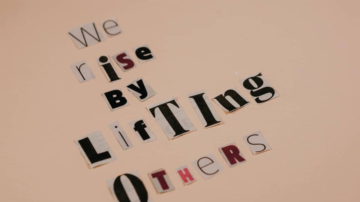 Cutout letters forming an inspirational quote on a beige background, encouraging positivity.