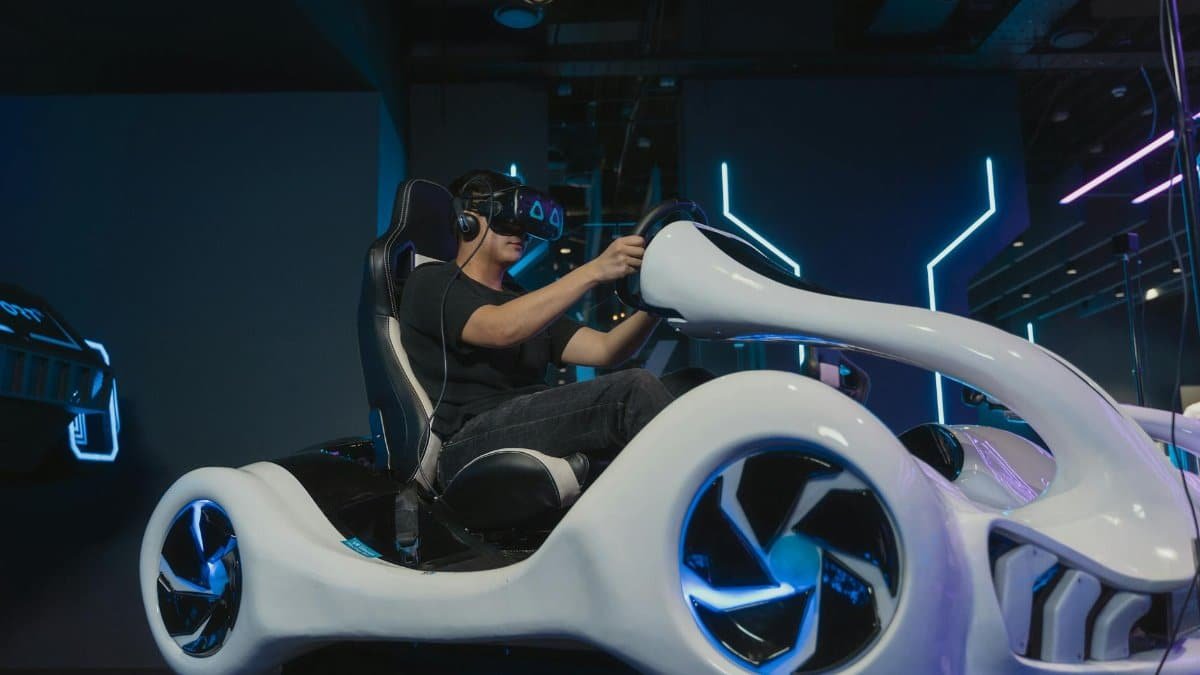 A young man engaging in a virtual reality driving simulation indoors with futuristic setup.