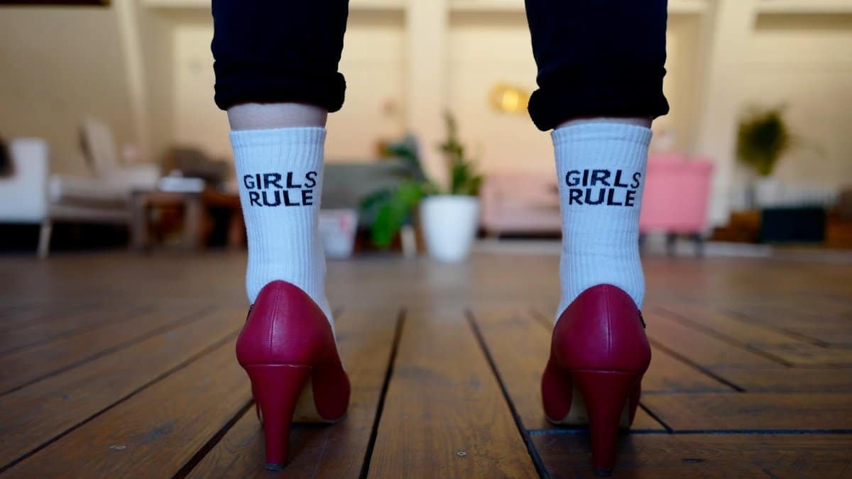 A bold fashion statement with red heels and 'Girls Rule' socks, symbolizing empowerment.