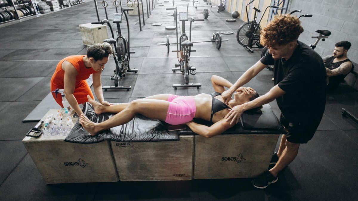 Athletes engage in recovery therapy with cupping and massage in a gym.