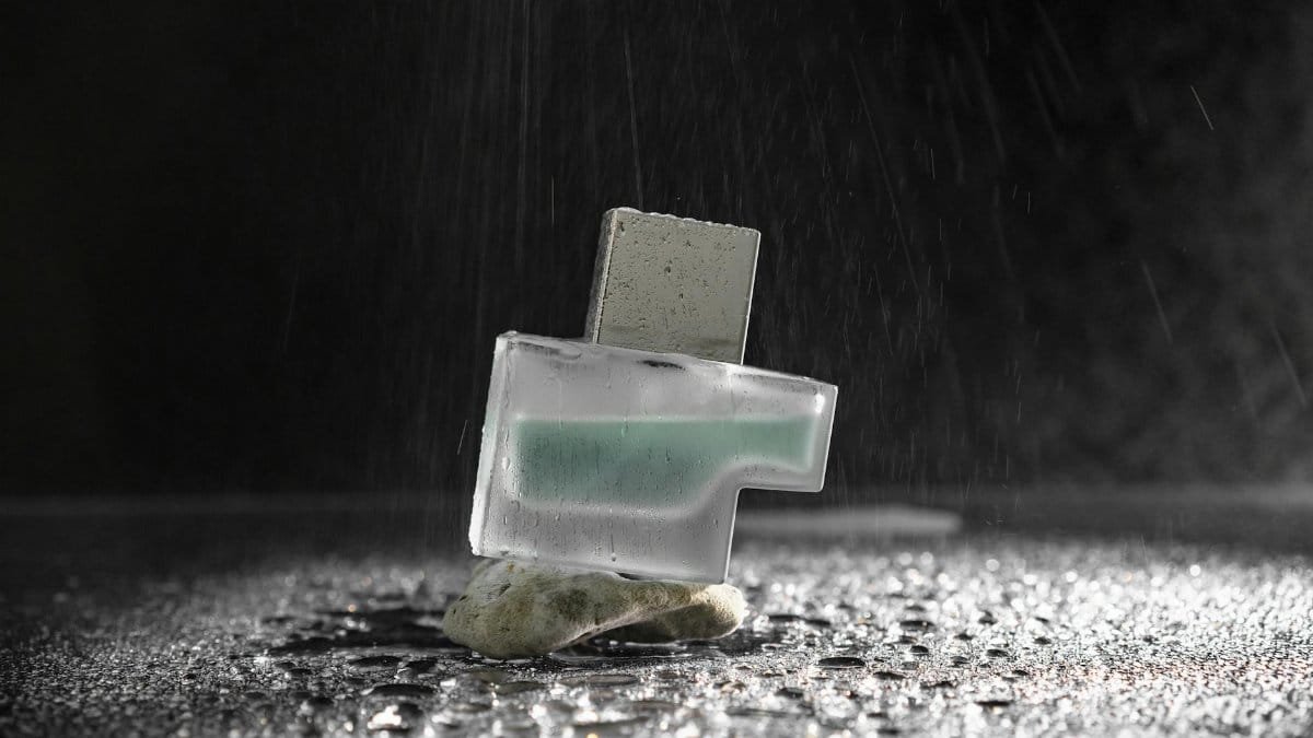 Stylish perfume bottle on textured surface, highlighted by water droplets for a fresh vibe.