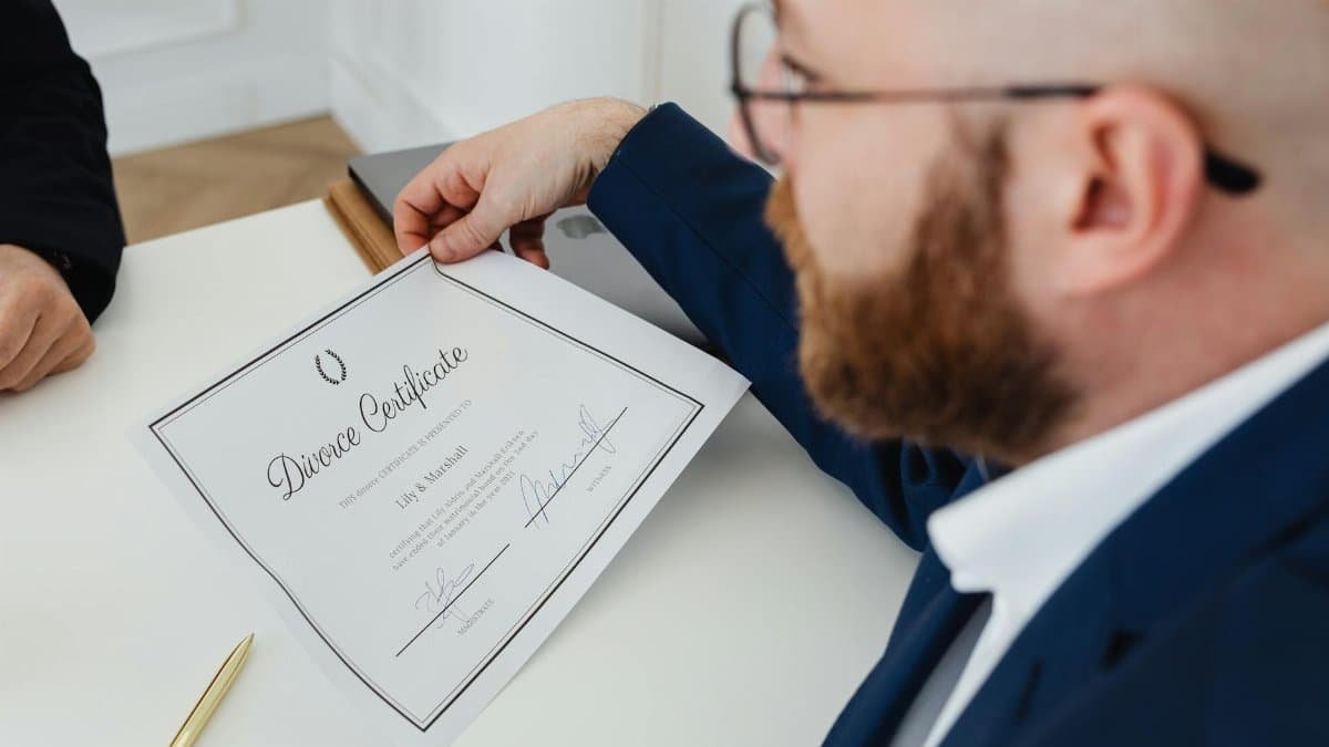 A man holding a divorce certificate in a formal office environment.