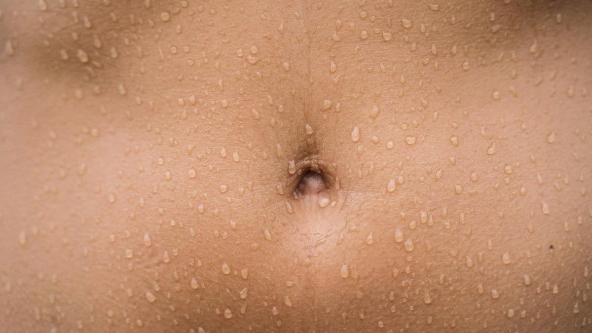 A detailed close-up image of a human belly with water droplets on the skin, showcasing texture.