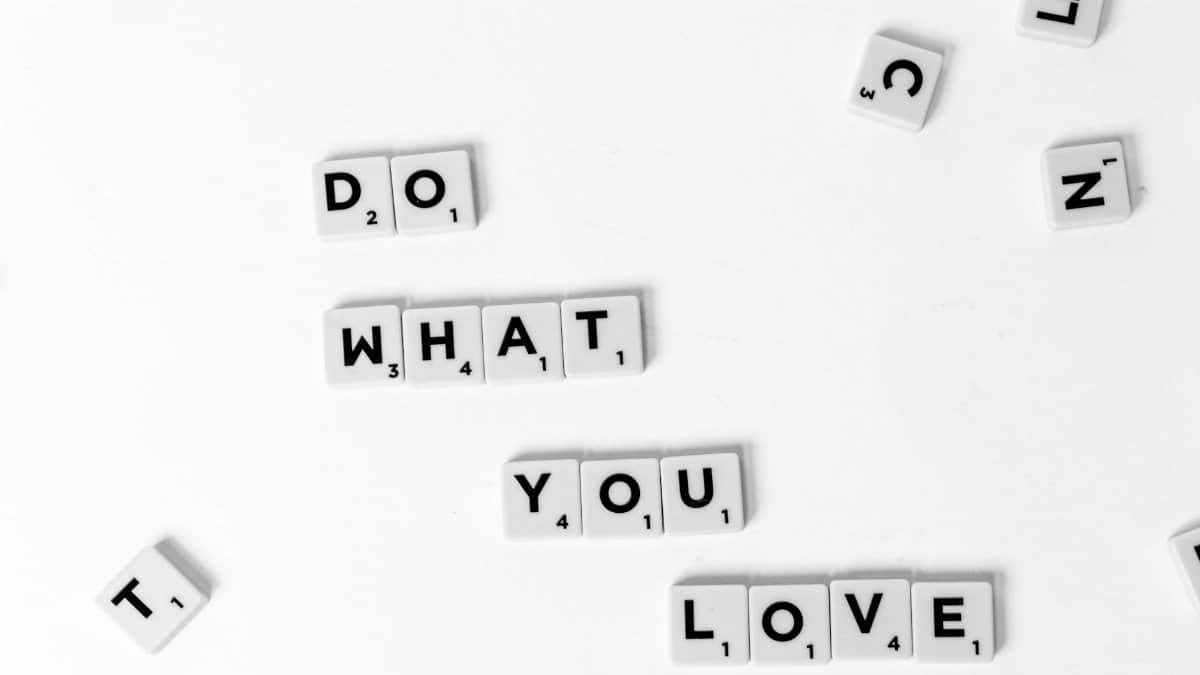 Scrabble tiles spelling 'Do What You Love' on a white background, encouraging creativity.