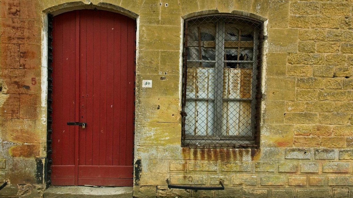 A rustic exterior with a red door and grungy stone wall, offering a vintage urban feel.