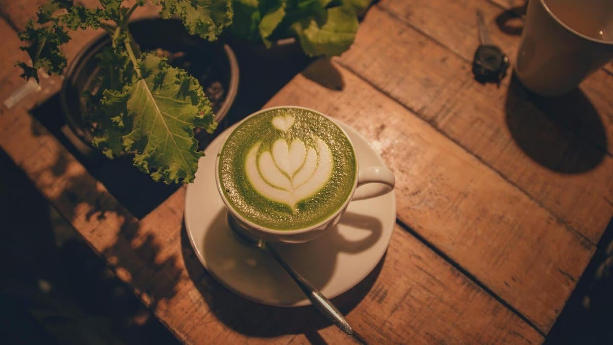 A warm indoor scene of a matcha latte with beautiful latte art on a rustic wooden table.
