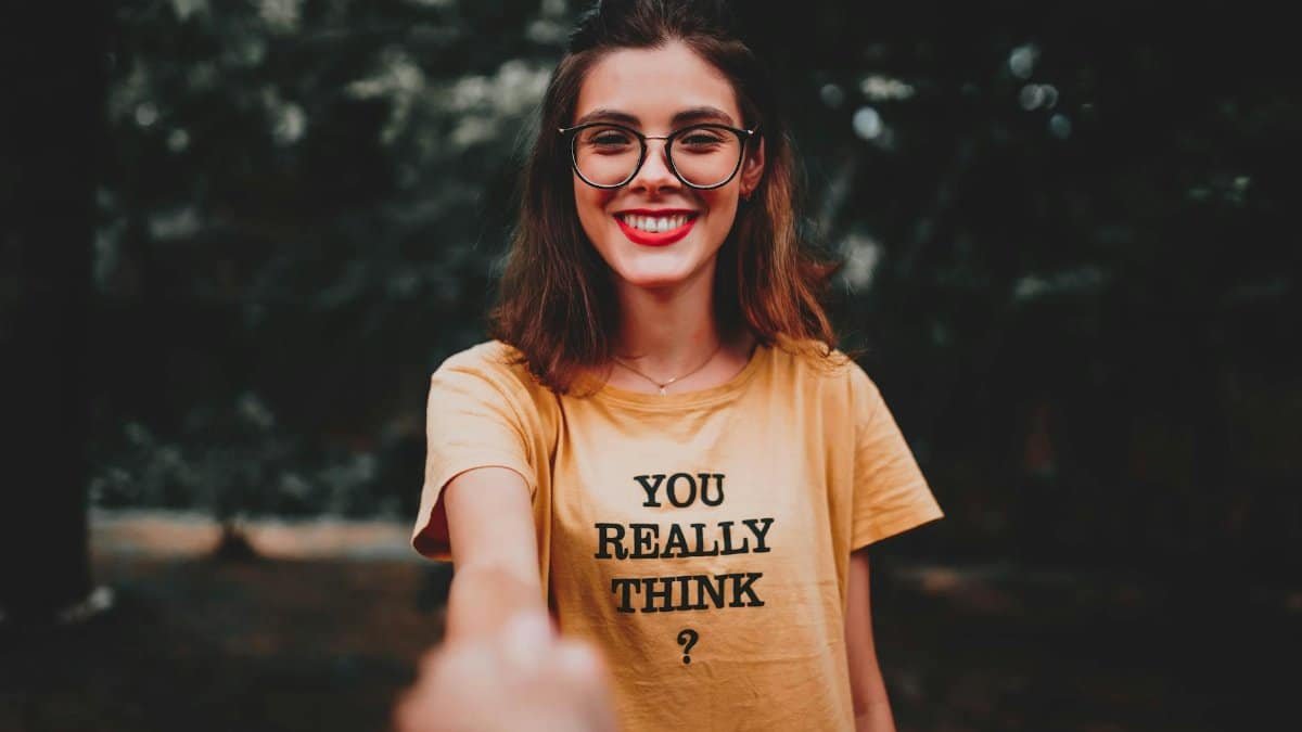 Portrait of a smiling woman with eyeglasses and yellow t-shirt outdoors.