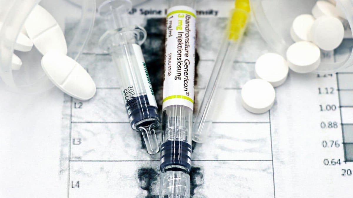 Close-up of syringes and pills on a bone density exam sheet, depicting osteoporosis treatment.
