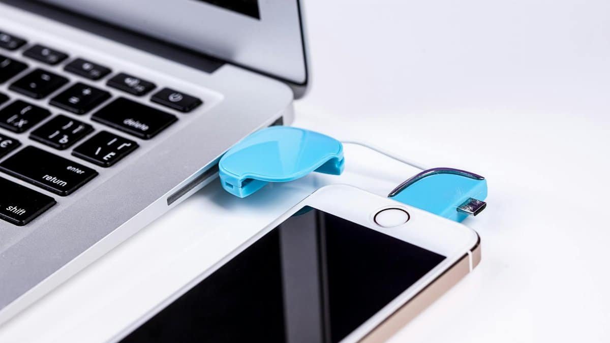 Close-up of a laptop and smartphone connected via USB cable for data transfer.