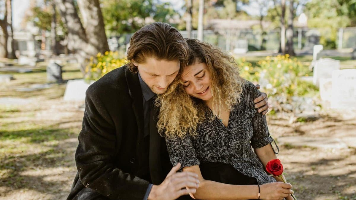 A comforting embrace in a serene graveyard captures grief and support.