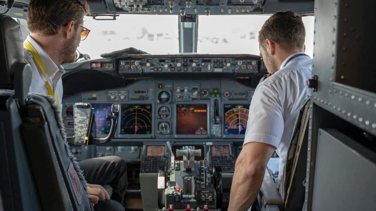 Two pilots navigating an aircraft cockpit, focused on advanced avionics and flight systems.