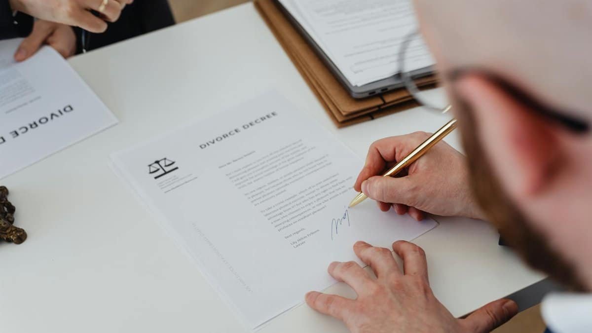 Close-up of a person signing a divorce decree on a desk.