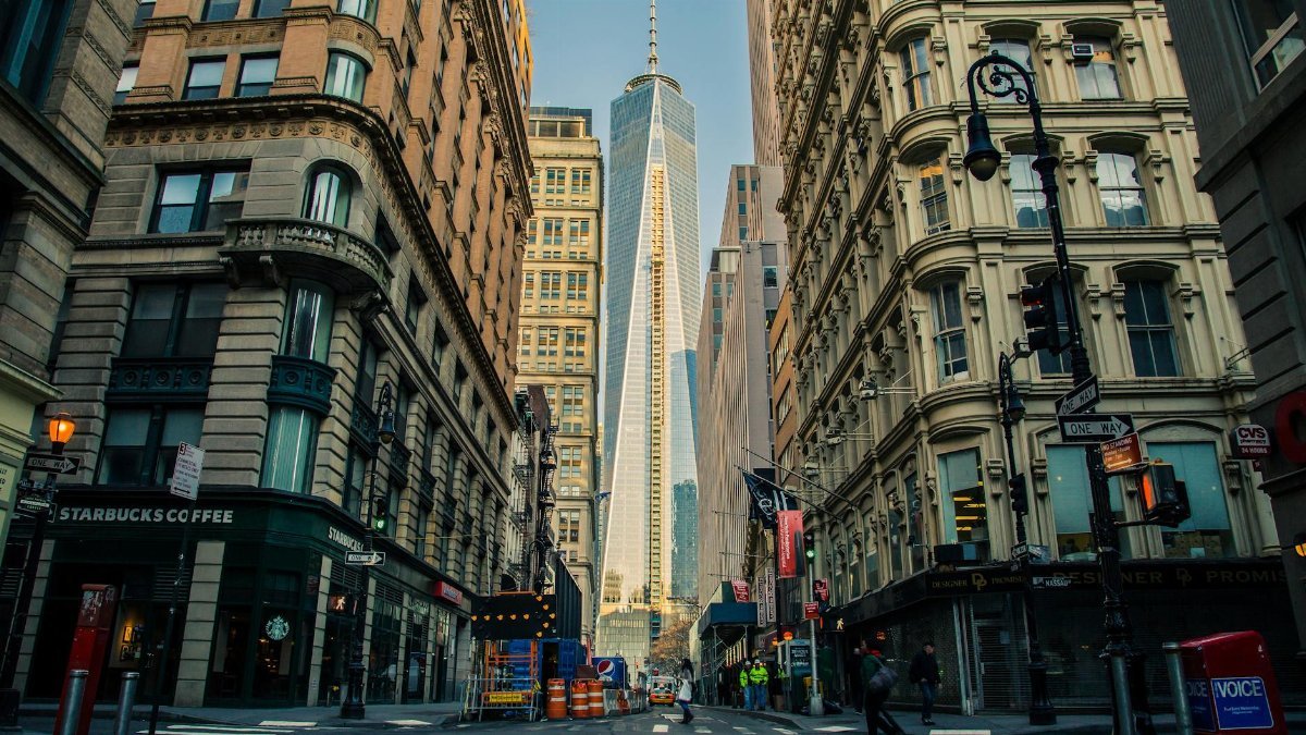 Street view of One World Trade Center in New York City surrounded by urban architecture and city life.