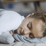 A young girl peacefully sleeping indoors, wrapped in a soft blanket for a serene moment.
