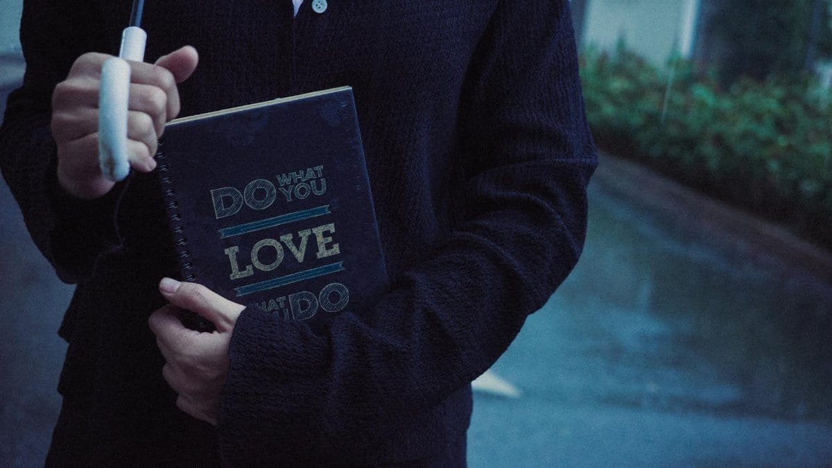 Close-up of person with umbrella holding a notebook on a rainy day.