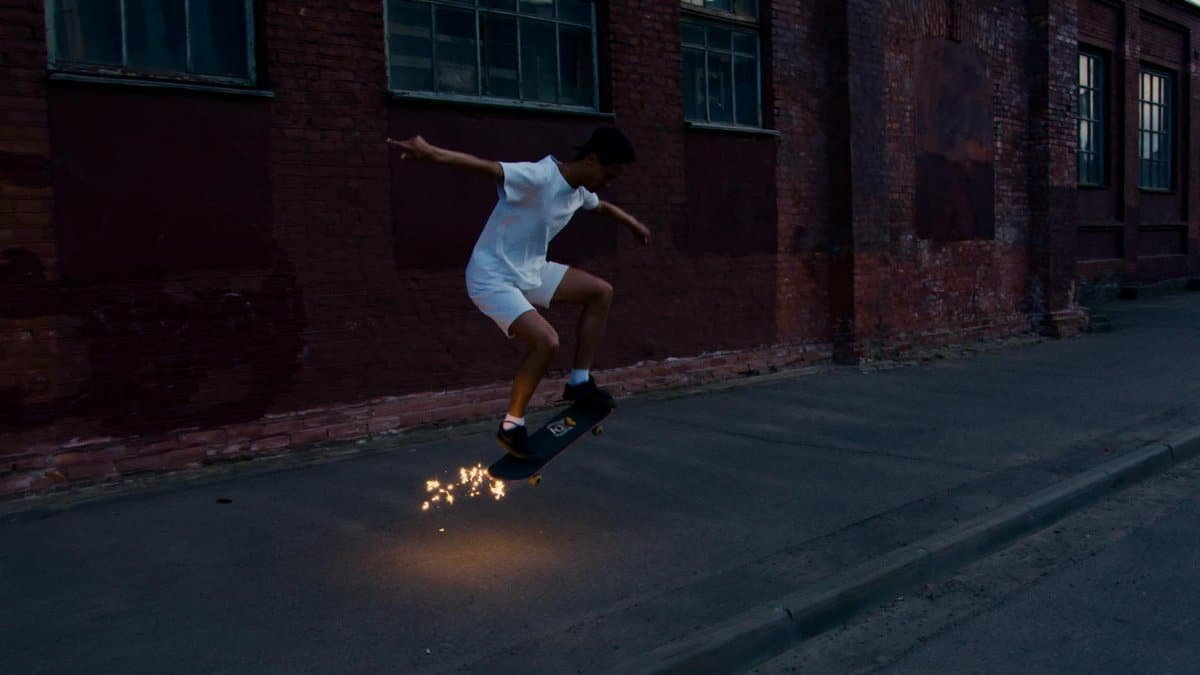 A skater executing a kickflip mid-air with sparks flying against a brick wall backdrop.