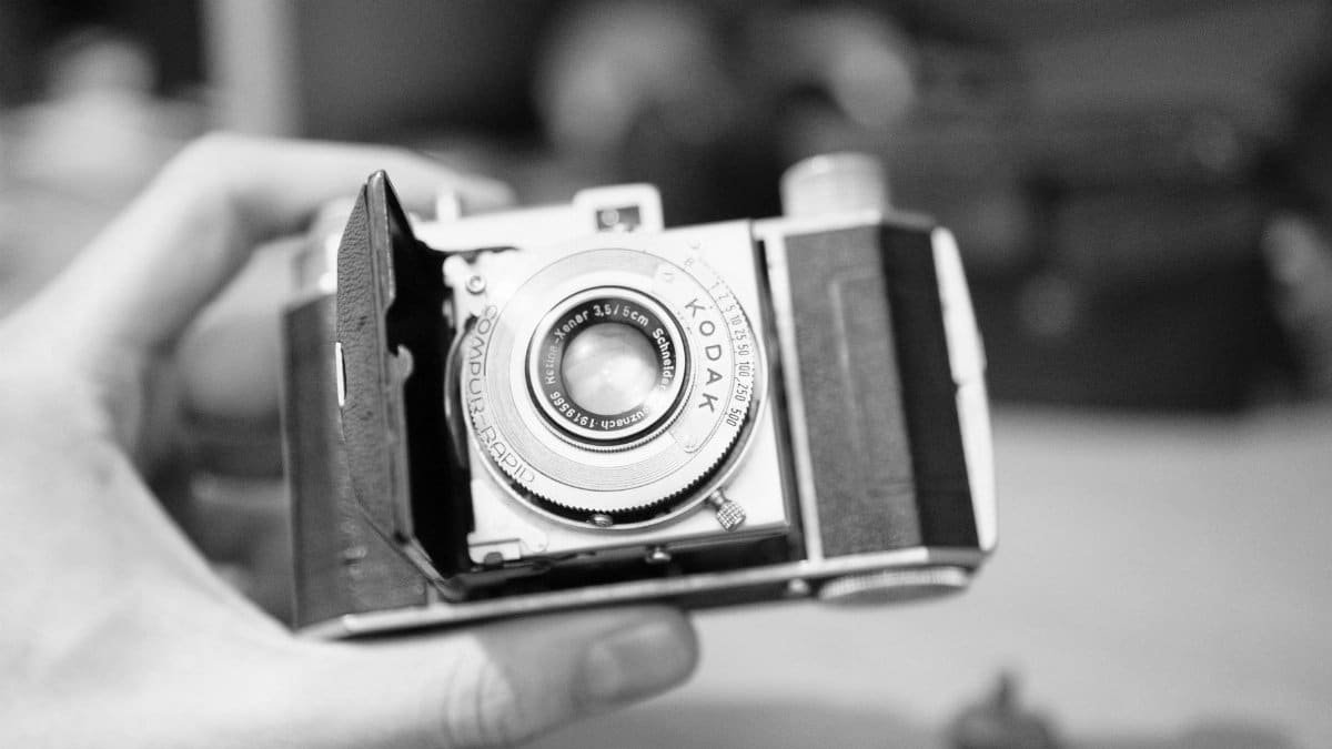 Close-up view of a classic vintage Kodak camera held in a gentle hand, evoking nostalgia.