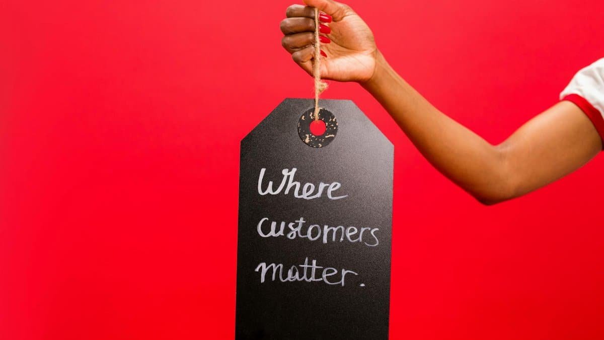 A hand holding a tag with 'Where customers matter' text on a vivid red background, emphasizing customer service.