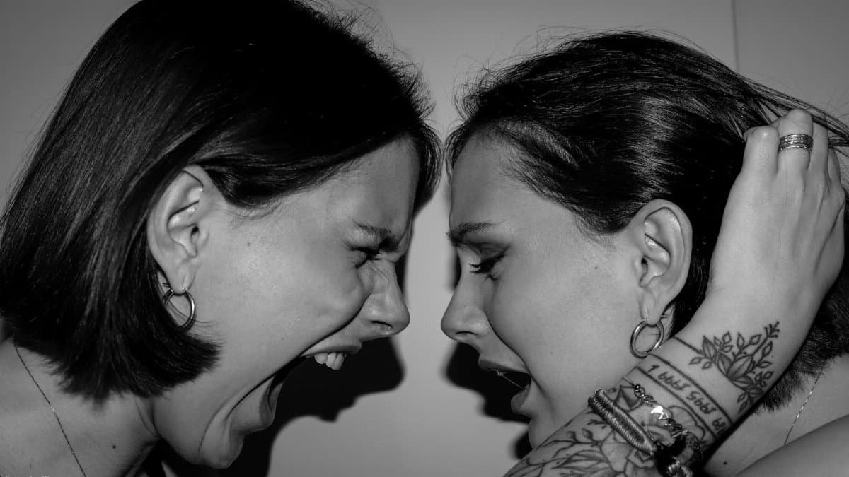 A dramatic black-and-white photo of two women shouting face-to-face, highlighting intense emotions.