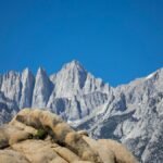 Capture the majestic Mount Whitney with its rugged peaks against a clear blue sky, showcasing natural beauty.