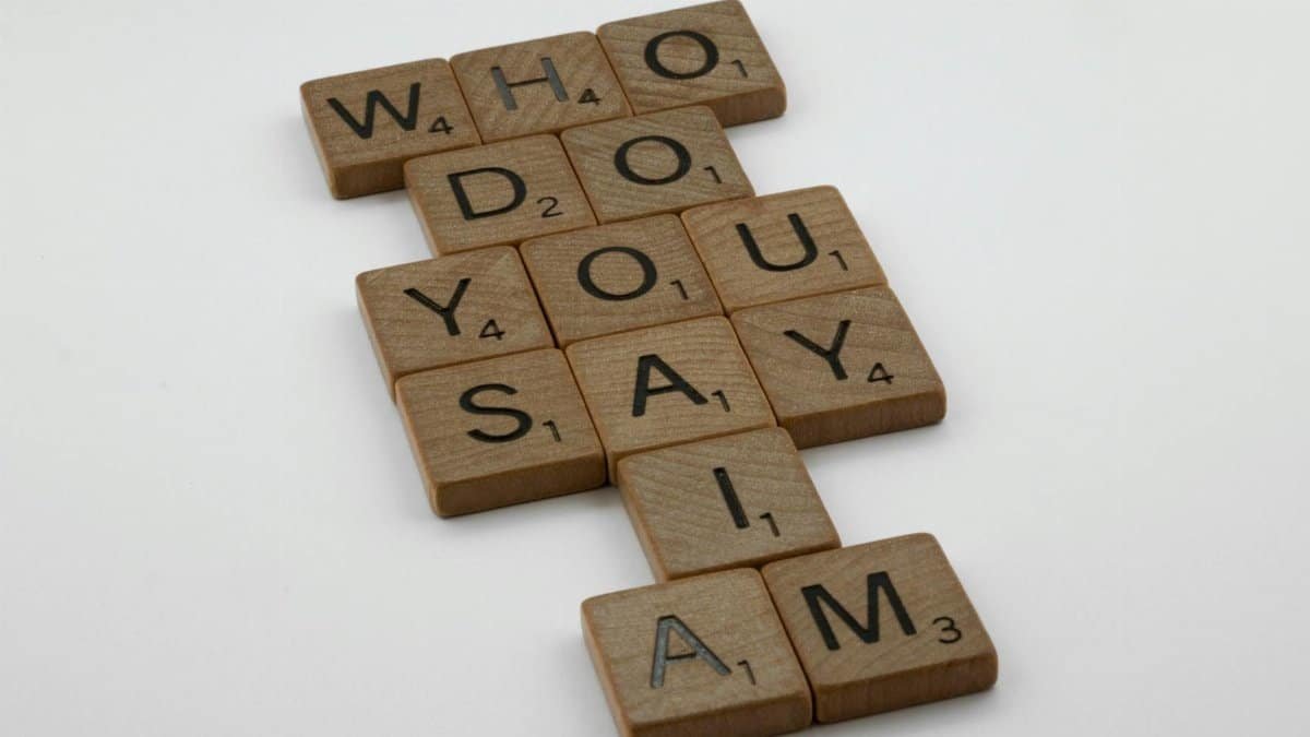 Wooden scrabble tiles arranged to spell 'Who do you say I am' on a white background.