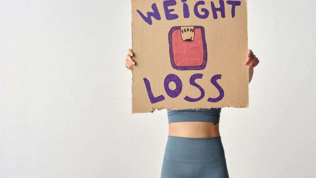 Person holding 'weight loss' sign for fitness motivation and health goals.