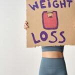 Person holding 'weight loss' sign for fitness motivation and health goals.