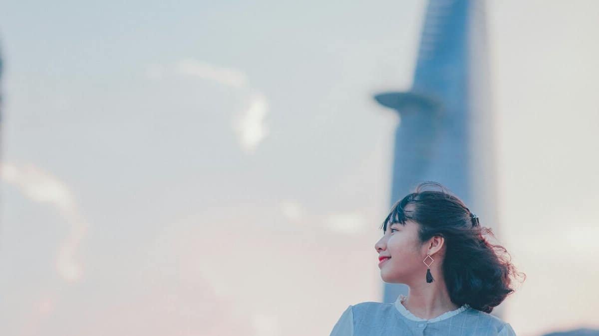 Portrait of a smiling woman in front of the Ho Chi Minh City skyline at sunset.