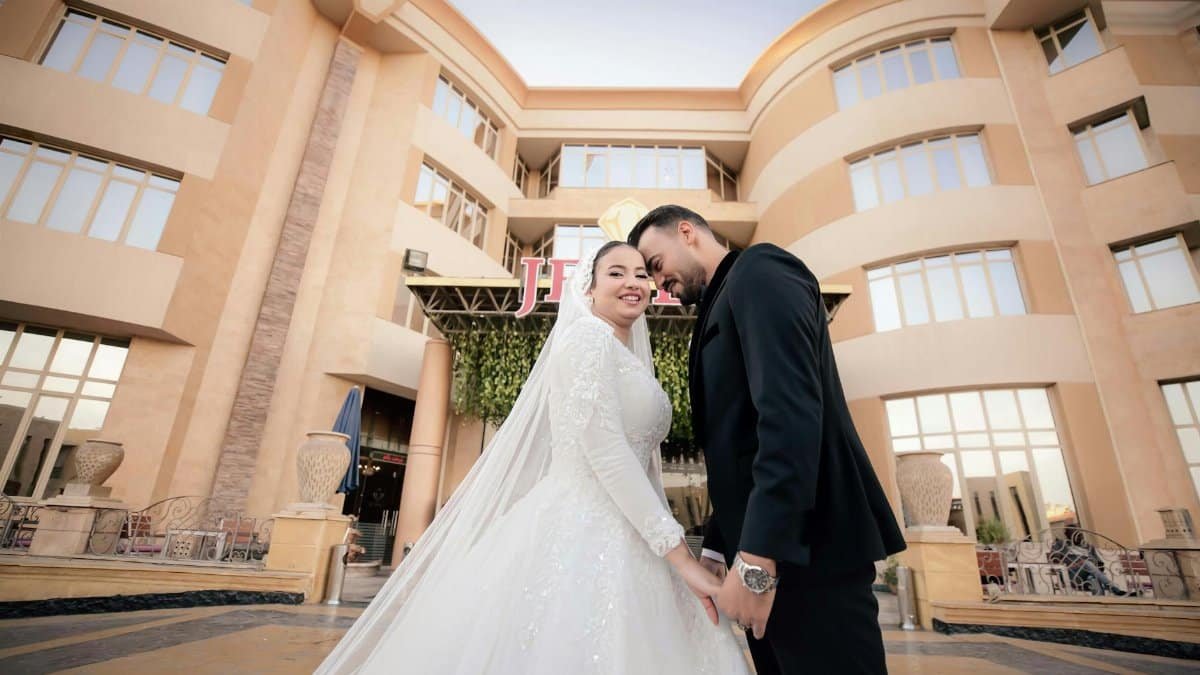 A joyful wedding couple poses elegantly in front of a grand building, capturing a moment of love.