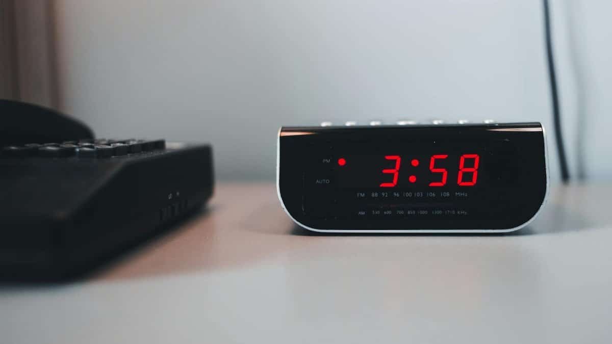 Close-up of a digital alarm clock displaying 3:58 PM on a white surface, signifying technology and time.