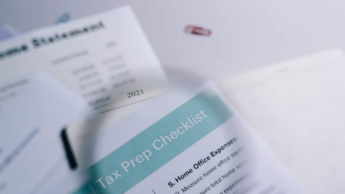 Close-up of tax preparation checklist and income statement with paperclips.