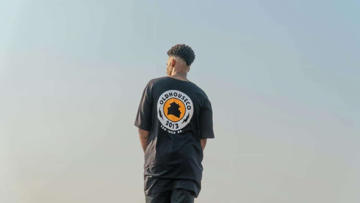 A person in a black shirt with a logo stands outdoors, showcasing a modern style.