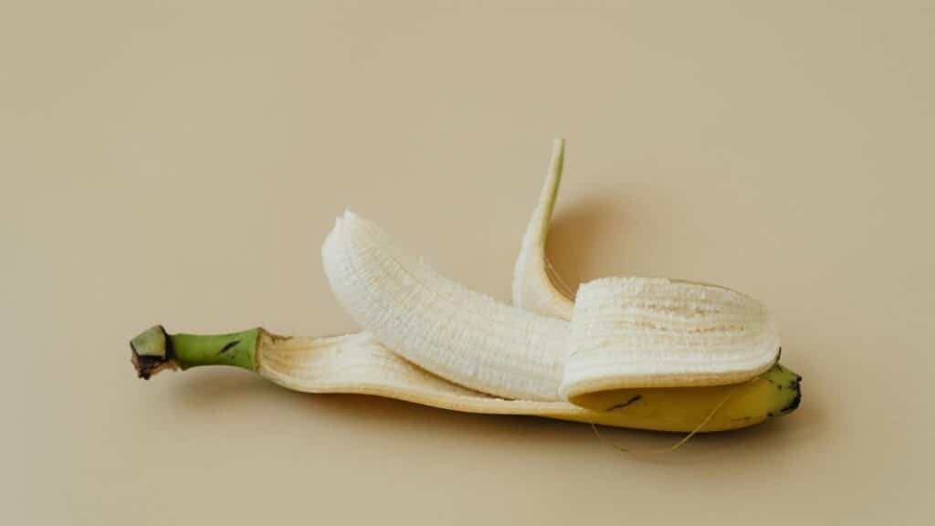 A peeled banana displayed on a soft beige background in a minimalist style.