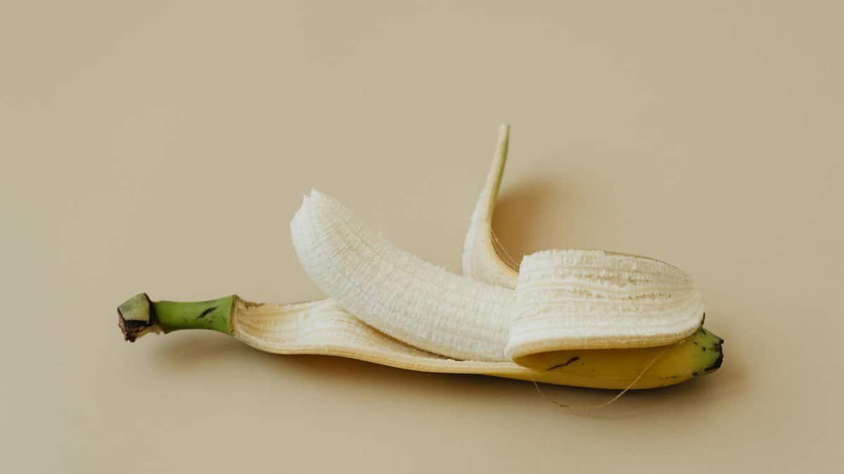 A peeled banana displayed on a soft beige background in a minimalist style.
