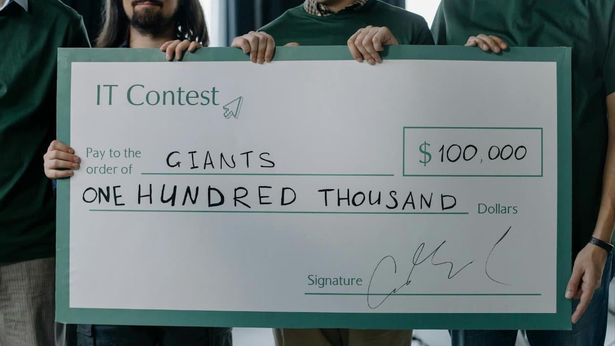 Group of men holding a $100,000 prize check after winning an IT contest.