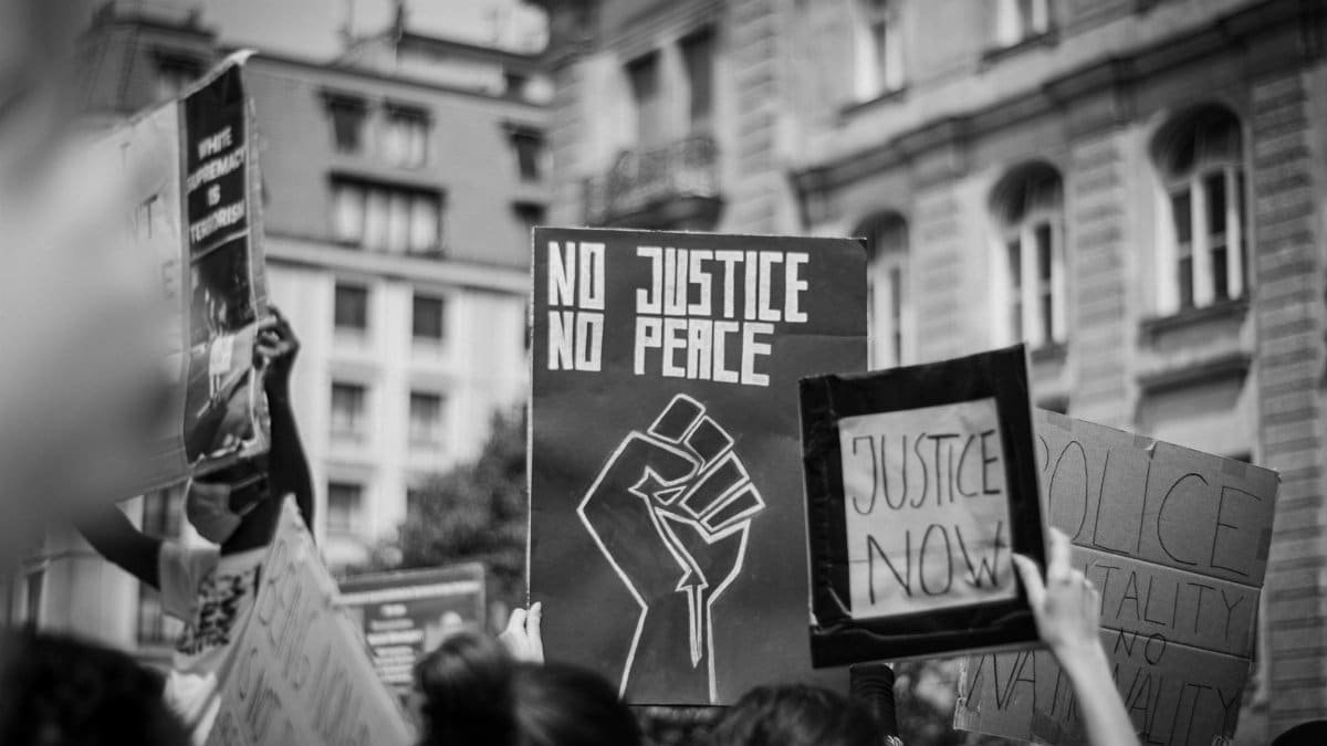Black and white photo of protesters with justice and peace signs demanding social change.