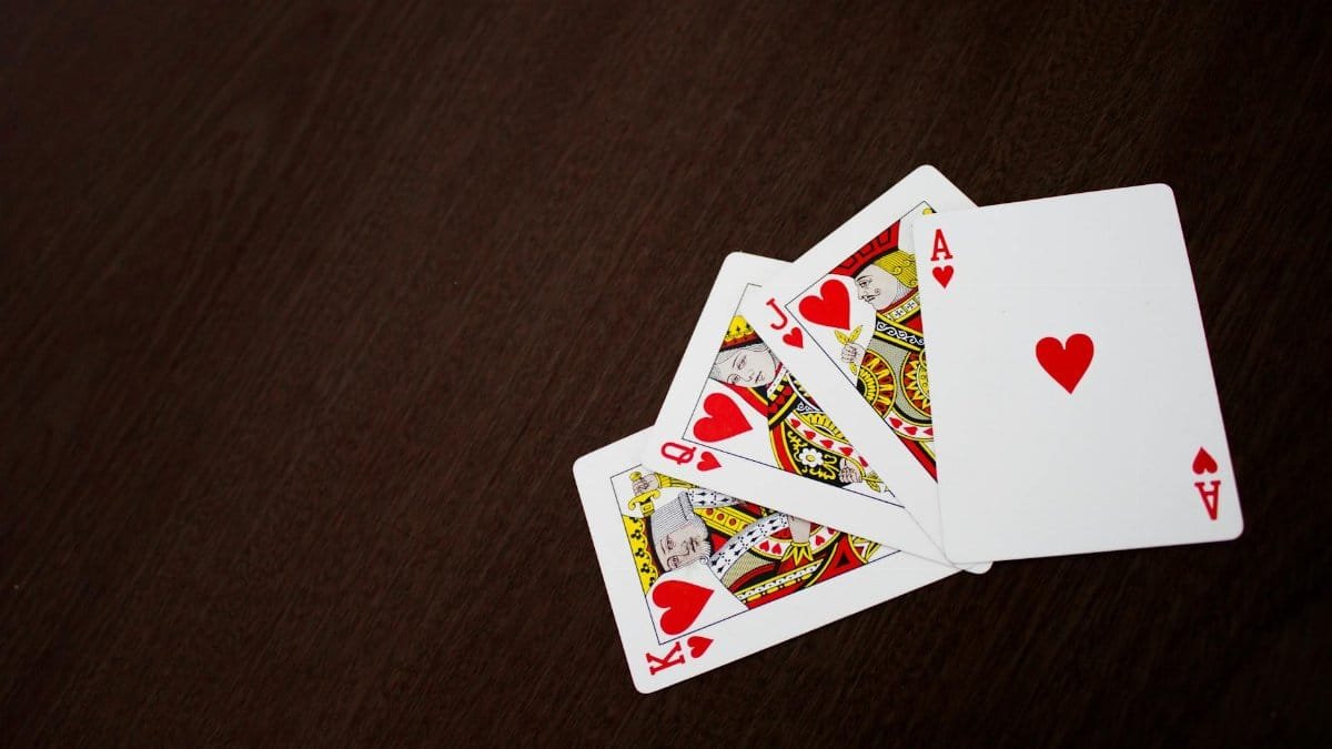 Elegant flat lay of playing cards featuring ace of hearts on a wooden surface.